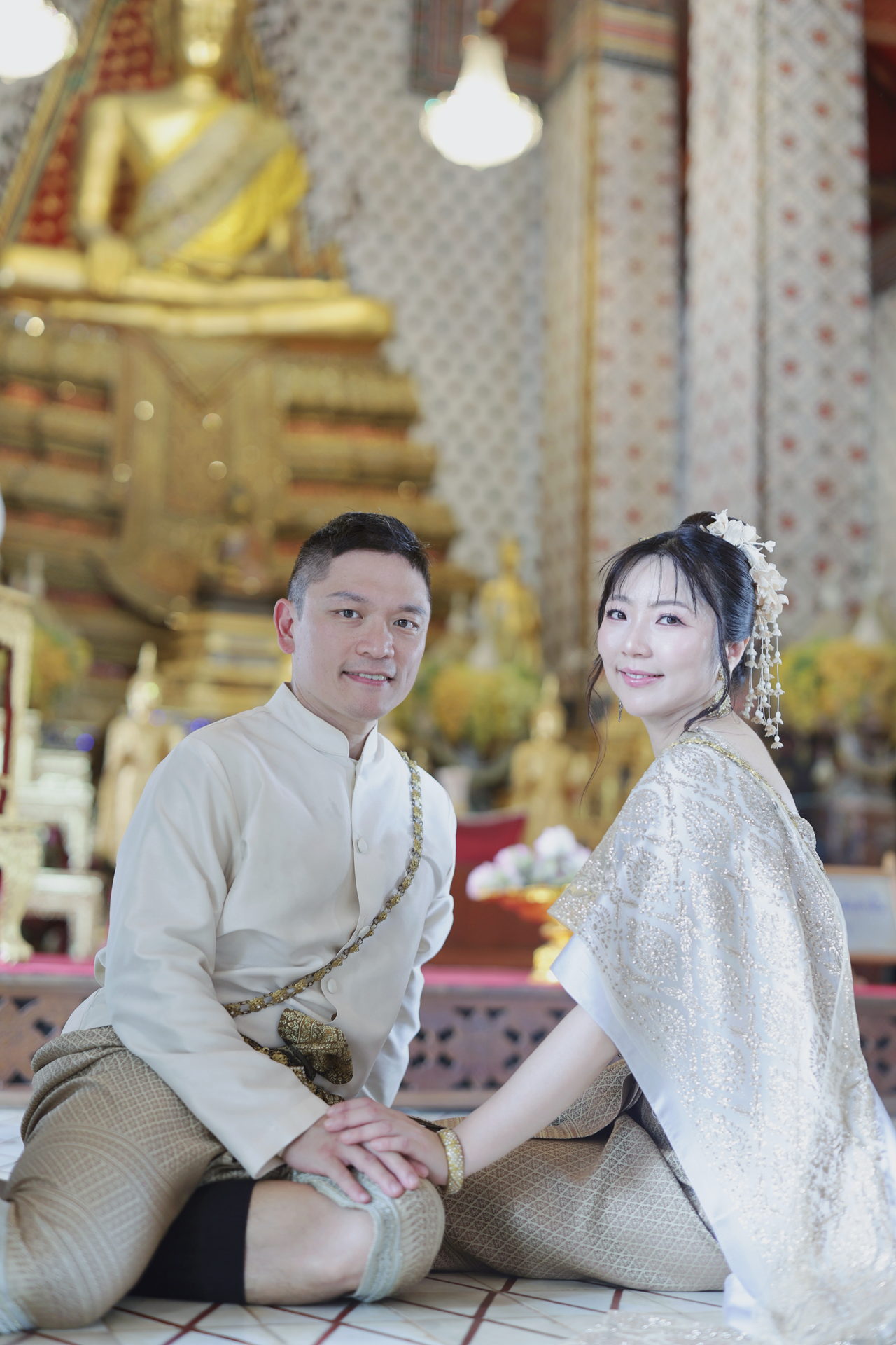 兩人並坐在金色佛像前的寺廟殿內